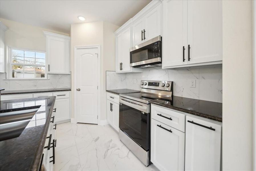 Kitchen featuring white cabinets, appliances with stainless steel finishes, and tasteful backsplash