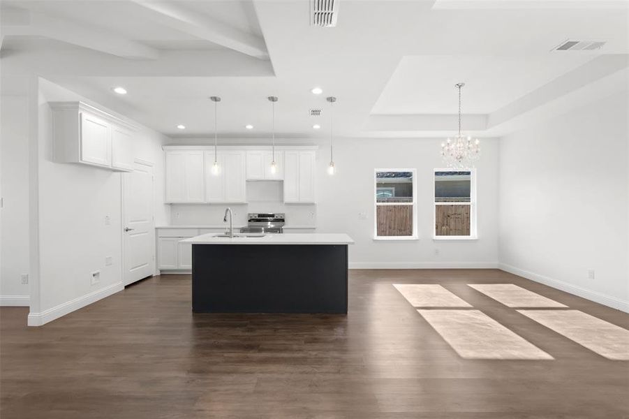 Kitchen featuring white cabinets, decorative light fixtures, and a center island with sink