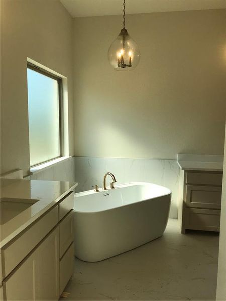 Bathroom featuring vanity, wainscoting, a soaking tub, light marble finish flooring, and tile walls