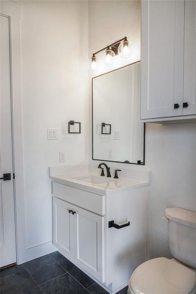 Bathroom featuring toilet, vanity, and tile patterned flooring