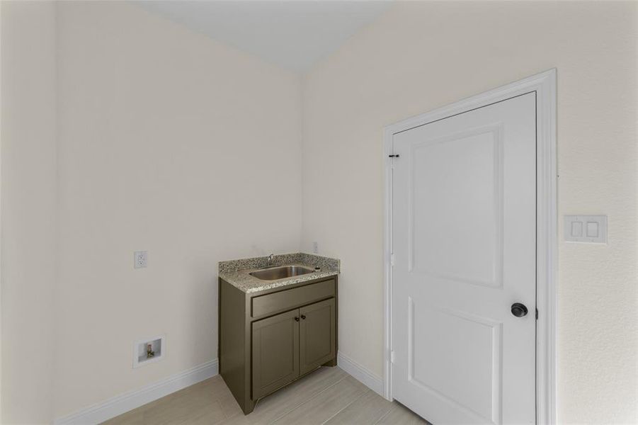 Laundry area featuring baseboards and a sink Laundry area featuring baseboards and a sink