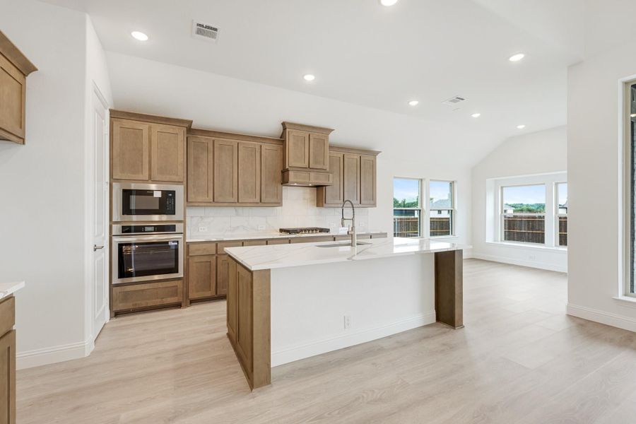 Kitchen with tan wood cabinets, stainless steel appliances, and large center island with white countertop Kitchen with tan wood cabinets, stainless steel appliances, and large center island with white countertop
