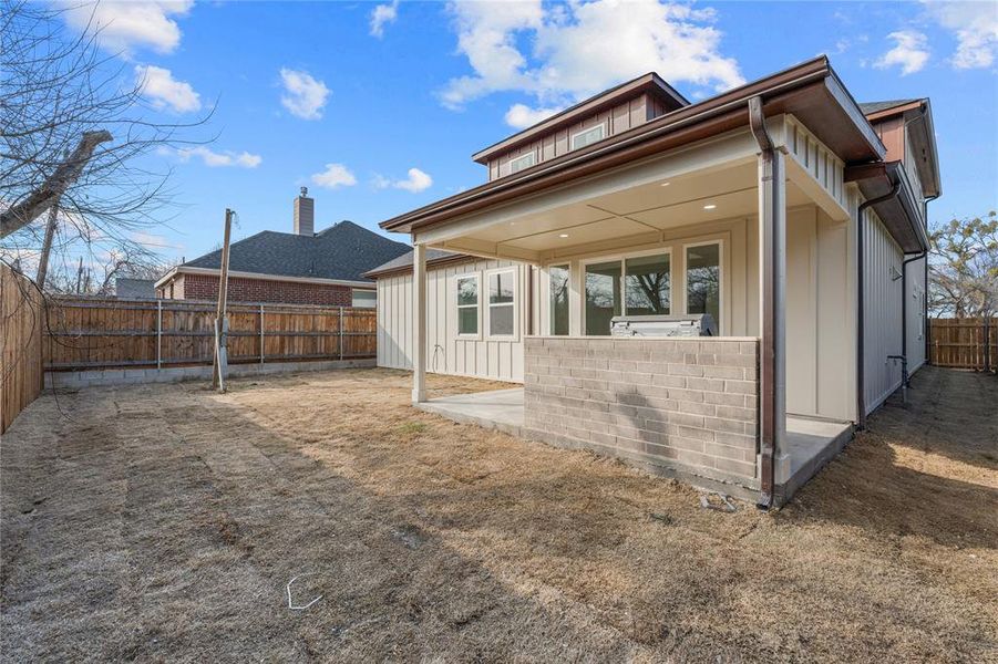 Rear view of property with a patio, a fenced backyard, and board and batten siding Rear view of property with a patio, a fenced backyard, and board and batten siding