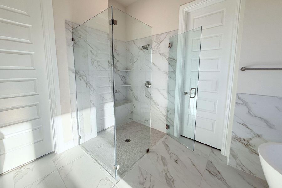 Bathroom featuring marble look tiles, a marble finish shower, and a soaking tub