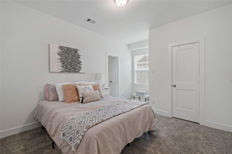 Cozy bedroom featuring soft carpeting, a plush bed with decorative pillows, and ample natural light from a large window, creating a serene retreat. Cozy bedroom featuring soft carpeting, a plush bed with decorative pillows, and ample natural light from a large window, creating a serene retreat.