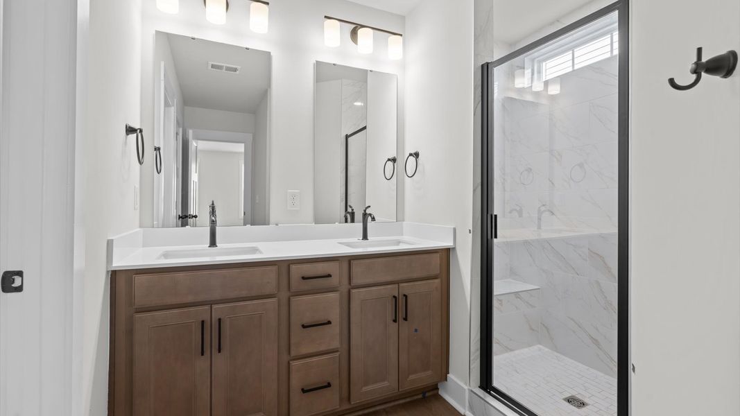 Spacious and modern primary bathroom with tiled walk-in shower and first-class double vanity setup