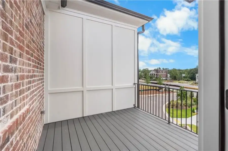 THIS OPEN BALCONY OFF THE OWNERS SUITE IS A SWEET SPOT FOR RELAXING,  with brick exterior wall, panel siding, TREX DECKING, and black metal railing