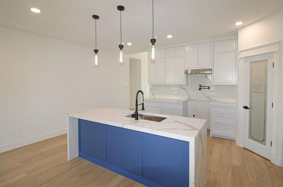 Kitchen with white cabinets, light wood finished floors, recessed lighting, light stone counters, and pendant lighting Kitchen with white cabinets, light wood finished floors, recessed lighting, light stone counters, and pendant lighting