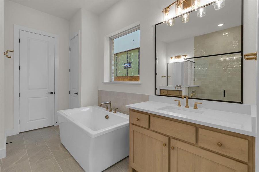 Modern bathroom featuring a freestanding soaking tub, single vanity with light-tone wood cabinetry, and a spacious walk-in shower with a glass enclosure