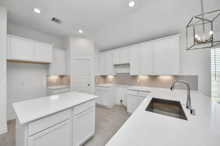 This kitchen is truly a chef's dream! This haven Boasts high ceilings, recessed & pendant lighting, stained wood cabinets, granite countertops, stainless steel appliances, a modern tile backsplash.  All of this overlooks your expansive family room, creating a perfect space for culinary delights and family gatherings. Sample photo of completed home with similar floor plan. Actual colors and selections may vary.