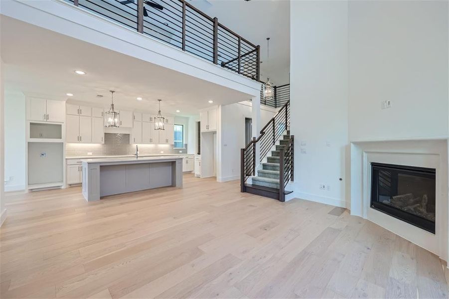 Unfurnished living room featuring a notable chandelier, sink, and light hardwood / wood-style flooring