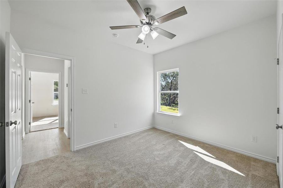 Carpeted spare room featuring ceiling fan, baseboards, and a smoke detector Carpeted spare room featuring ceiling fan, baseboards, and a smoke detector
