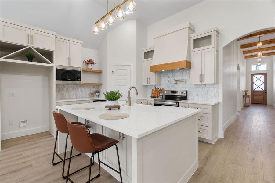 Kitchen featuring a kitchen breakfast bar, decorative backsplash, light stone countertops, beam ceiling, and stainless steel appliances Kitchen featuring a kitchen breakfast bar, decorative backsplash, light stone countertops, beam ceiling, and stainless steel appliances