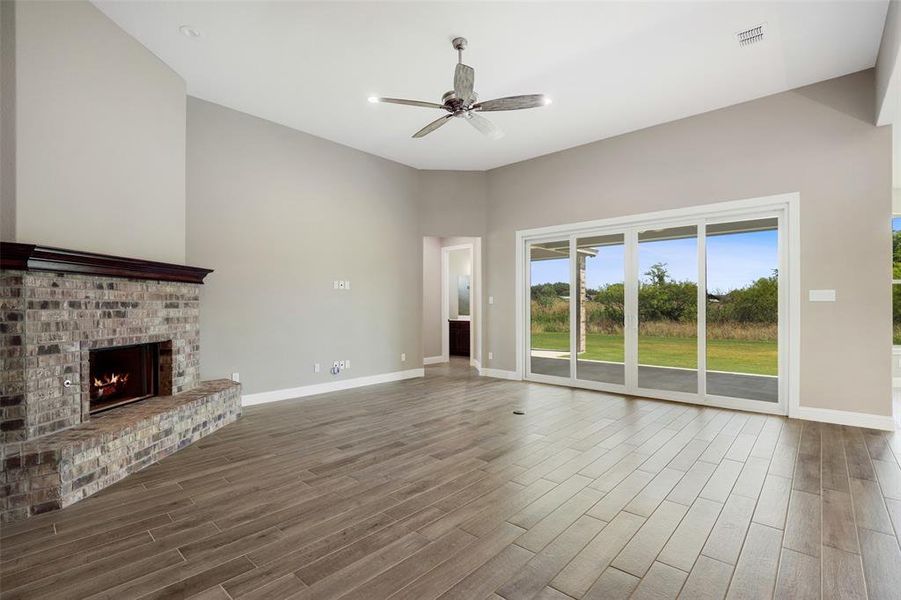 Unfurnished living room featuring ceiling fan, hardwood / wood-style flooring, and a brick fireplace