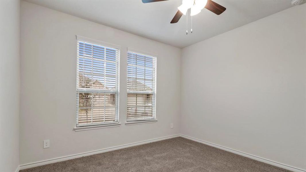 Spare room with ceiling fan and dark colored carpet