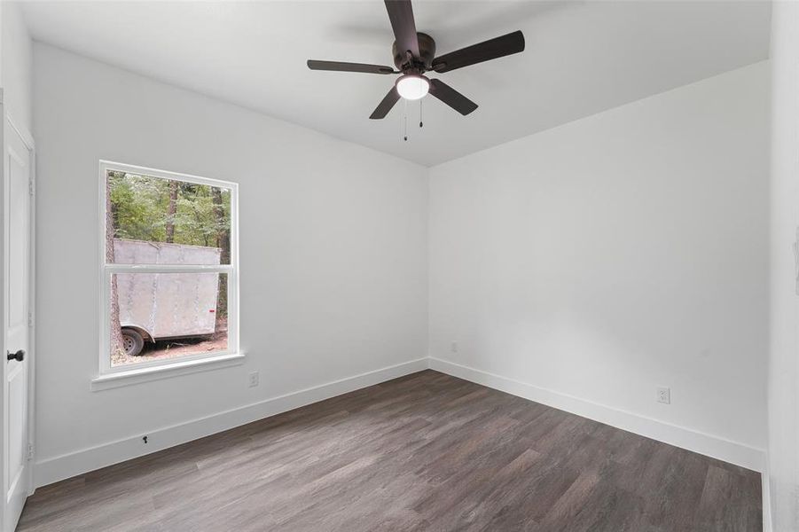 Bright interior space featuring a window with exterior views, wood-finish flooring, white walls, and a ceiling fan with integrated lighting Bright interior space featuring a window with exterior views, wood-finish flooring, white walls, and a ceiling fan with integrated lighting