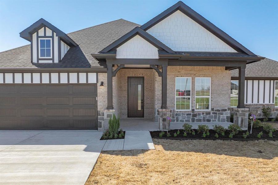 View of front of home with a porch, roof with shingles, concrete driveway, an attached garage, and brick siding