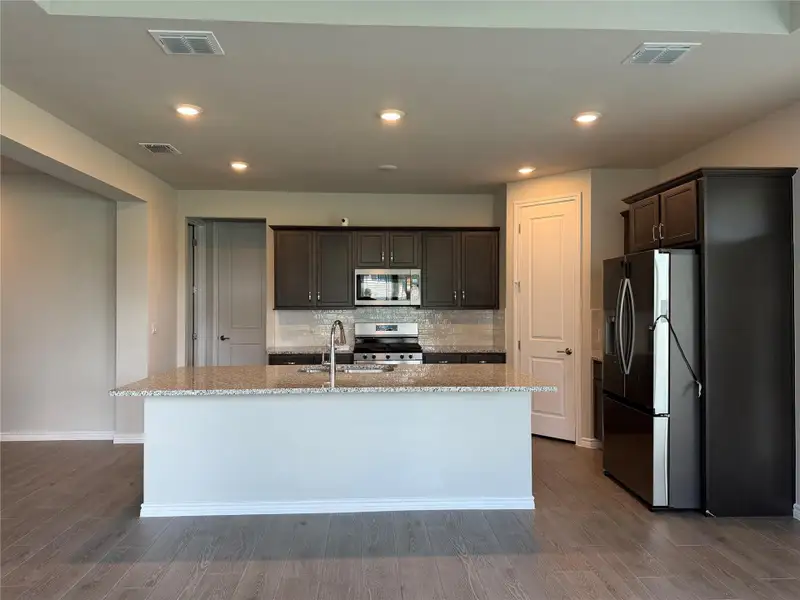 A generous kitchen island with granite counters anchors this sleek culinary space.