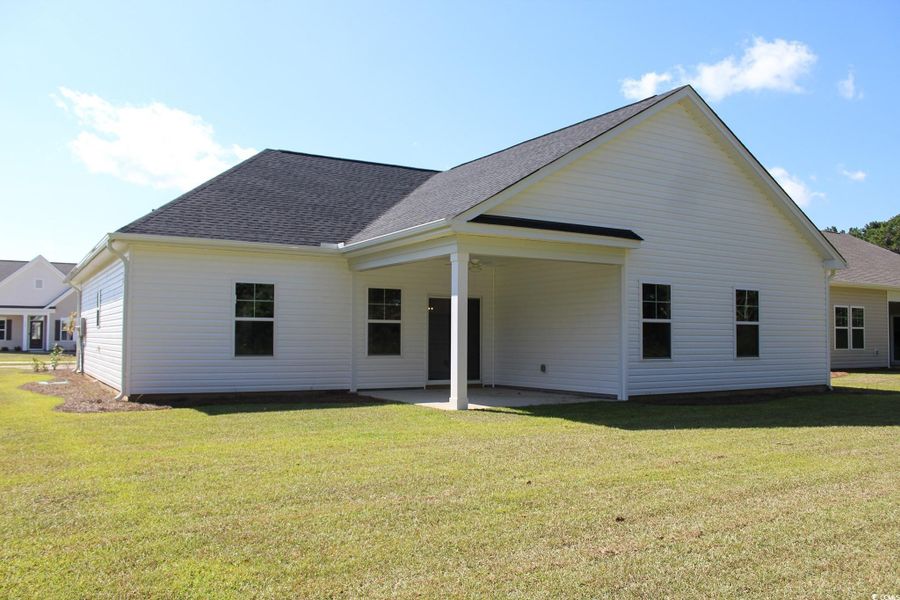 Rear view of house with a patio, a shingled roof, and a lawn
