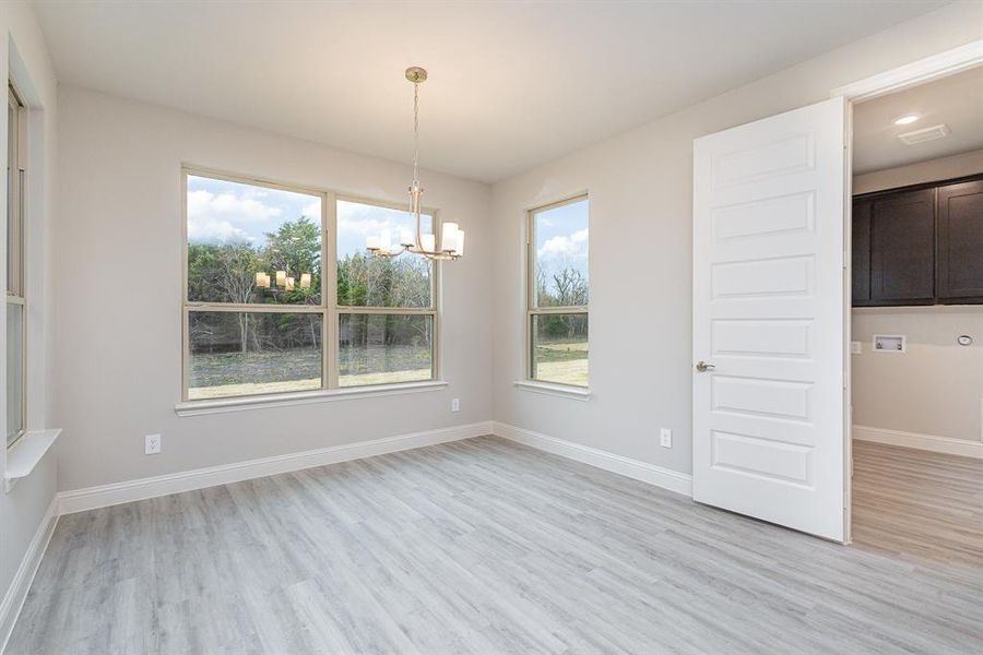 Unfurnished dining area with plenty of natural light, a chandelier, and light hardwood / wood-style flooring