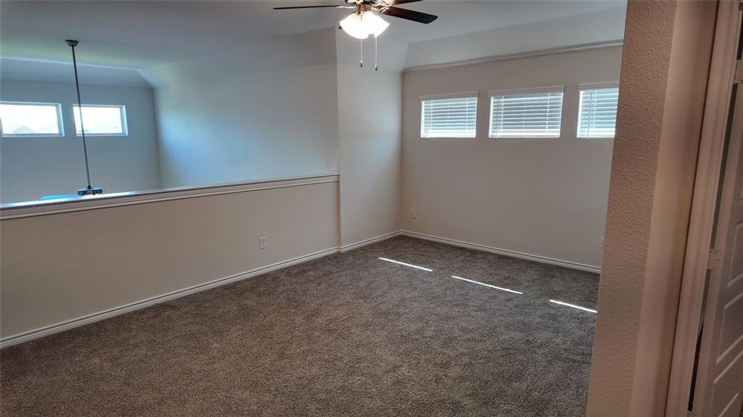 Spare room featuring ceiling fan, carpet flooring, and lofted ceiling