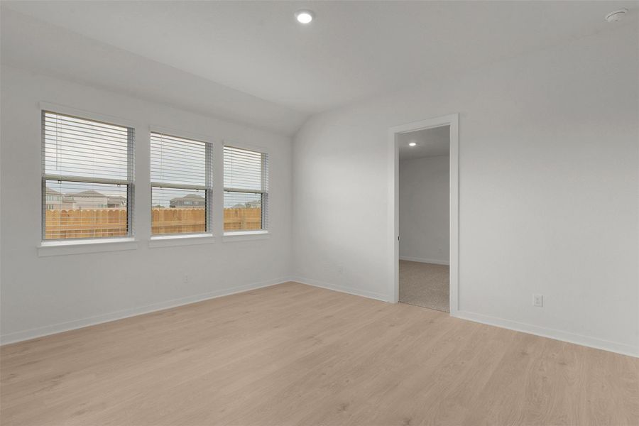 Empty room with light wood-style floors, vaulted ceiling, and recessed lighting