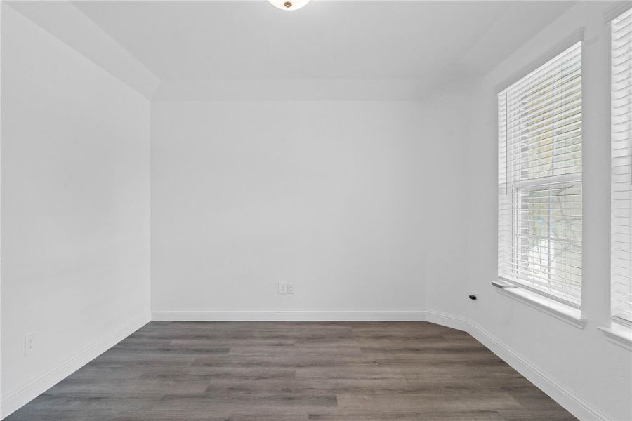 This handsome home office features luxury vinyl plank flooring, large windows with fitted blinds, high ceilings, lighting, and custom paint!