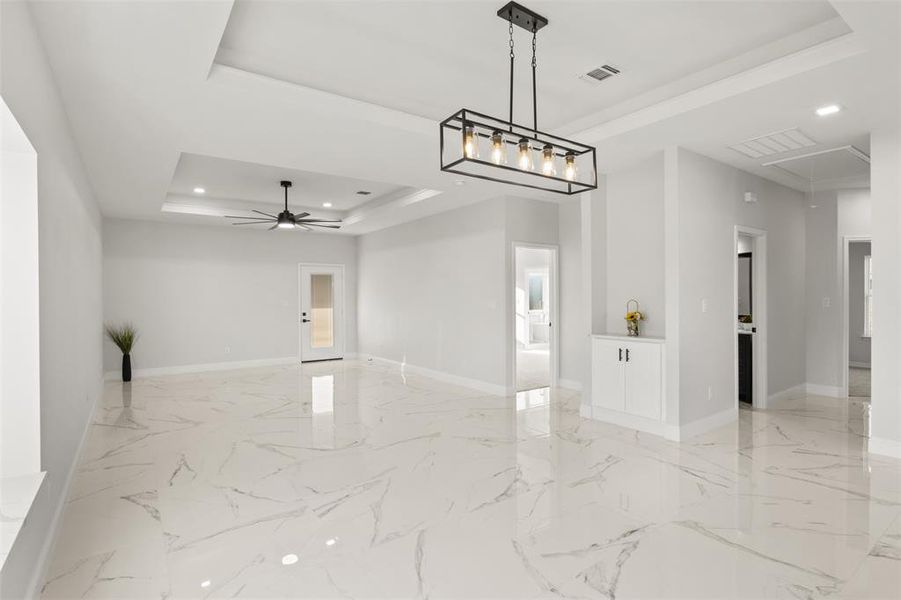 Family room with a tray ceiling, attic access, light marble finish floors, recessed lighting, and a ceiling fan