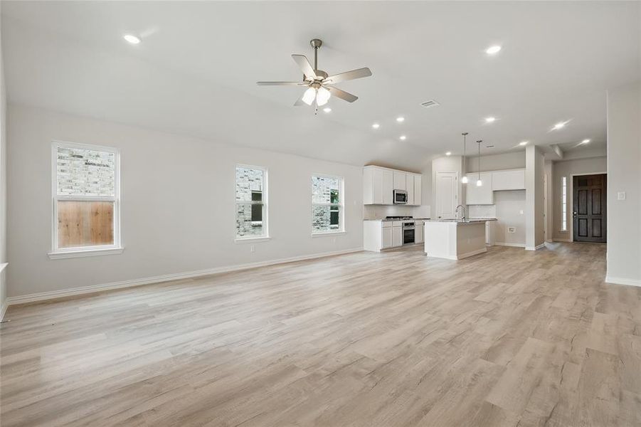 Unfurnished living room featuring a ceiling fan, light wood finished floors, baseboards, recessed lighting, and a sink