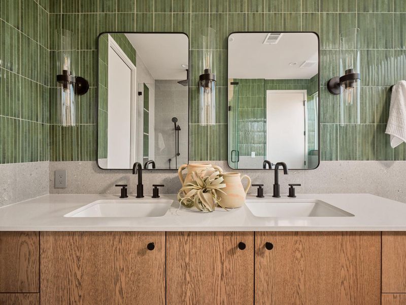 Bathroom with tiled shower, double vanity, and tile walls