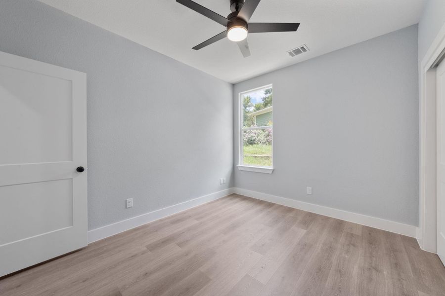 Light-filled interior space featuring wood-finish flooring, a contemporary ceiling fan, and a single window with white trim