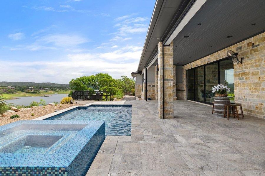 Outdoor living is elevated by a sparkling pool and integrated spa, surrounded by a limestone patio that offers front-row seats to the tranquil waterfront scenery of Lake Travis.