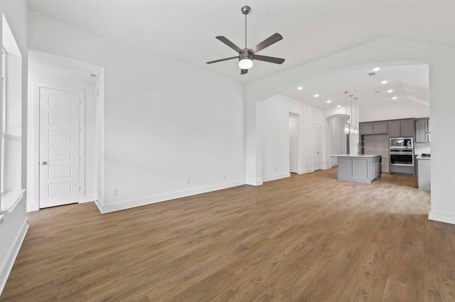 Unfurnished living room with a ceiling fan, recessed lighting, baseboards, wood finished floors, and arched walkways