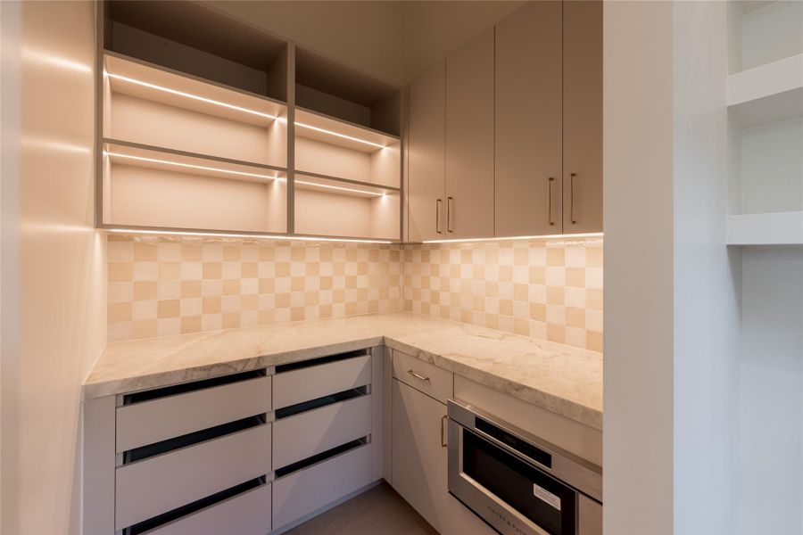 Integrated lighting turns the butler’s pantry into a design moment of its own, illuminating generous cabinetry, natural stone counters and dedicated prep space while keeping the working side of the kitchen discreetly tucked away. Integrated lighting turns the butler’s pantry into a design moment of its own, illuminating generous cabinetry, natural stone counters and dedicated prep space while keeping the working side of the kitchen discreetly tucked away.