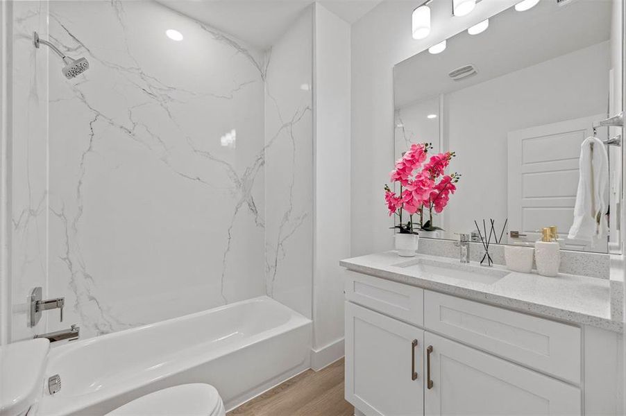 Bathroom featuring shower / bath combination, visible vents, toilet, wood finished floors, and vanity