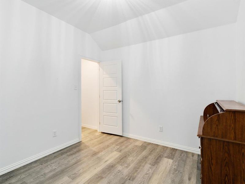 Room featuring wood-finish flooring, white baseboards, and a five-panel interior door