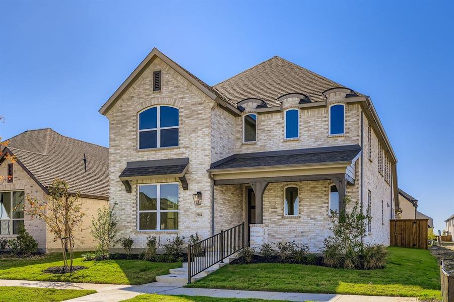 French country inspired facade featuring brick siding, a porch, and roof with shingles French country inspired facade featuring brick siding, a porch, and roof with shingles