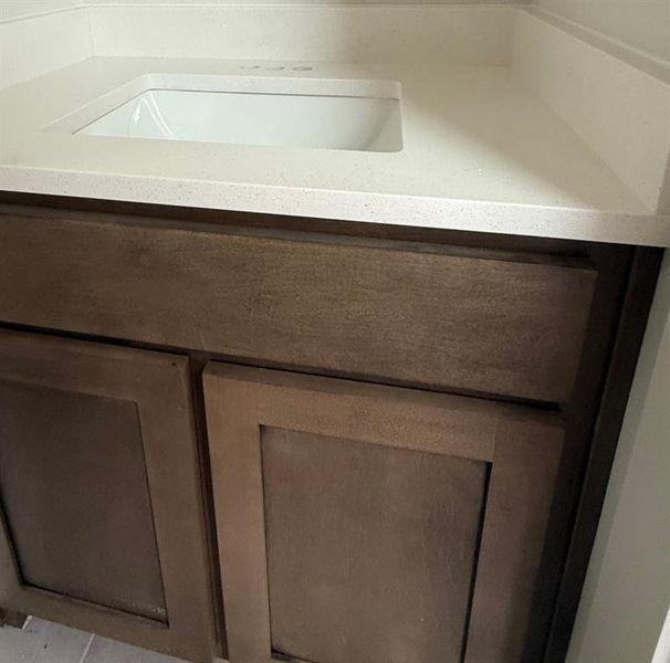 Integrated vanity sink with a light-toned countertop, wood-finish cabinetry, and built-in drawer Integrated vanity sink with a light-toned countertop, wood-finish cabinetry, and built-in drawer