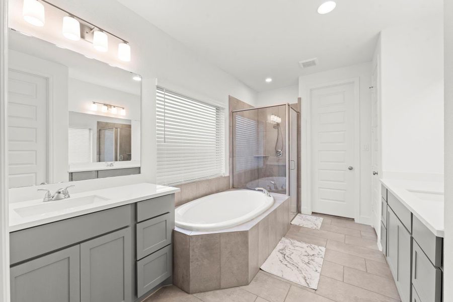 Truly a retreat for getting ready on a busy morning or stealing away for an evening out, your en-suite bath features elegant double door entry, rectangular tile flooring, recessed lighting, dual vanities, soaking tub, shower, window with rain-glass and blinds for privacy, linen closet, private commode, and huge walk-in closet.