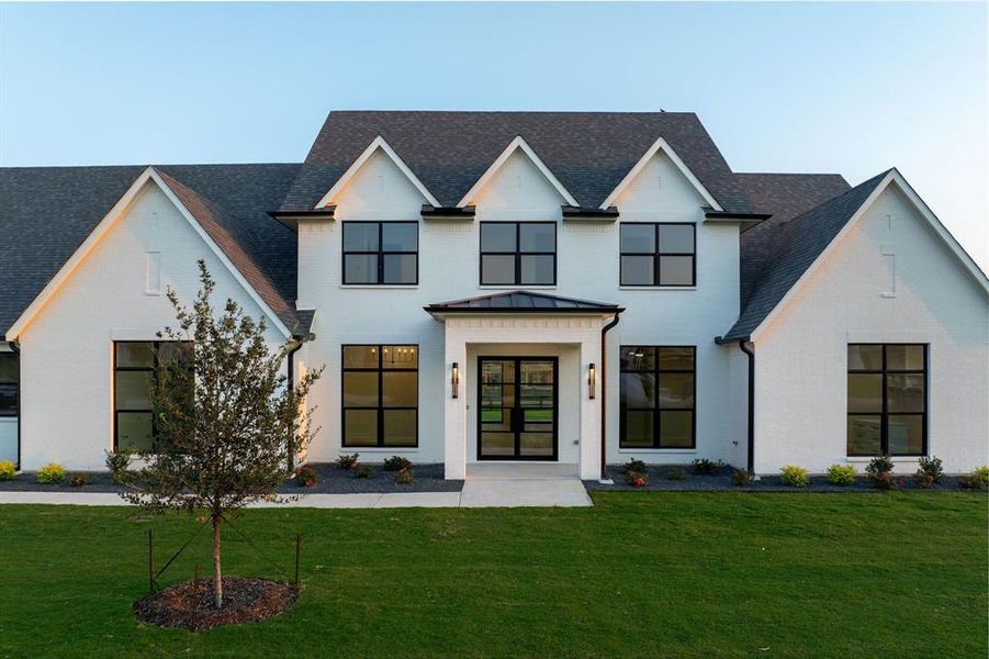 Modern farmhouse style home with a front yard, a standing seam roof, brick siding, a metal roof, and a shingled roof Modern farmhouse style home with a front yard, a standing seam roof, brick siding, a metal roof, and a shingled roof