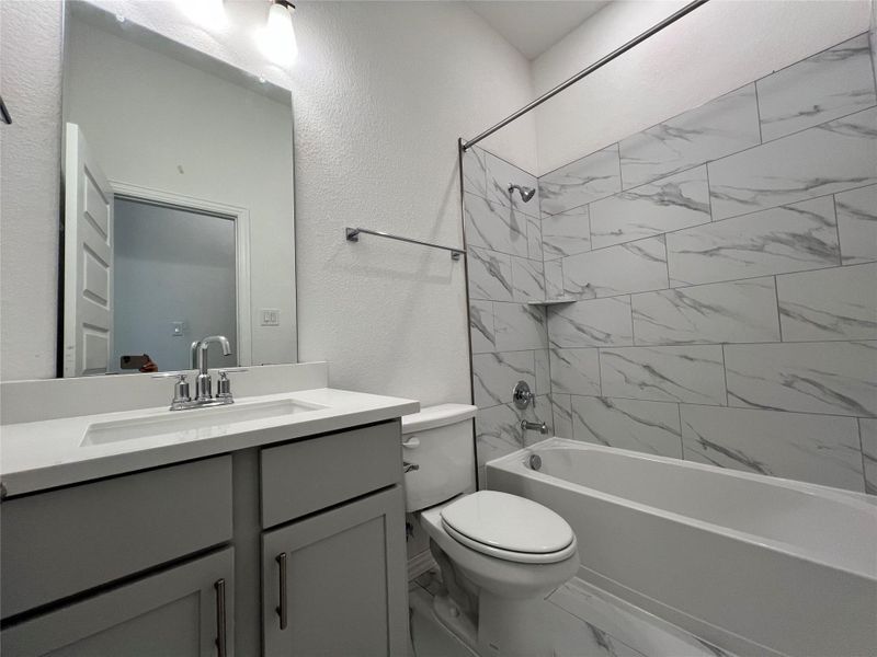 Bathroom with marble look tile flooring, vanity, a textured wall, and bathing tub / shower combination Bathroom with marble look tile flooring, vanity, a textured wall, and bathing tub / shower combination