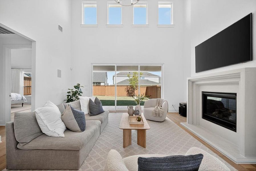 Living area with wood finished floors, plenty of natural light, a high ceiling, and a glass covered fireplace Living area with wood finished floors, plenty of natural light, a high ceiling, and a glass covered fireplace