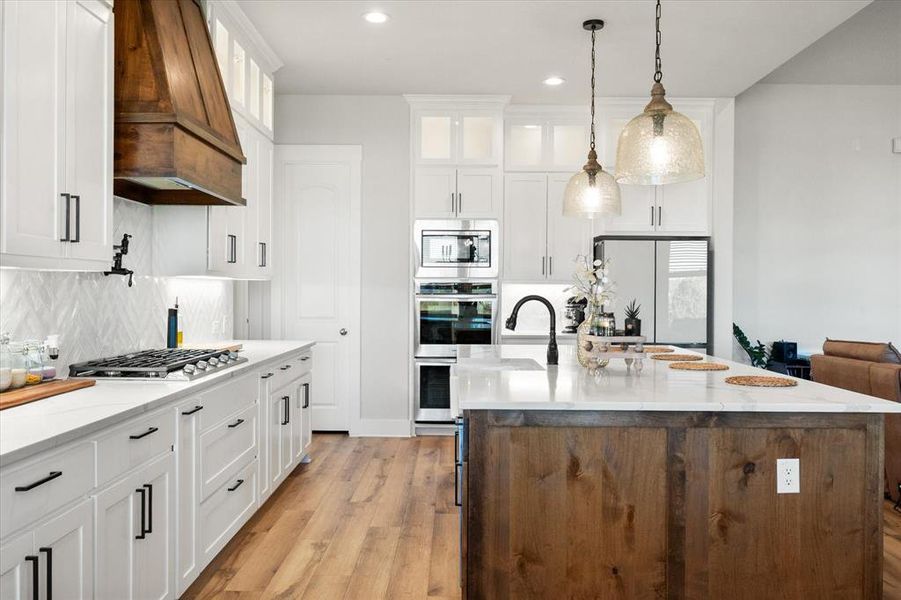 Kitchen with white cabinetry, light stone countertops, decorative light fixtures, and recessed lighting