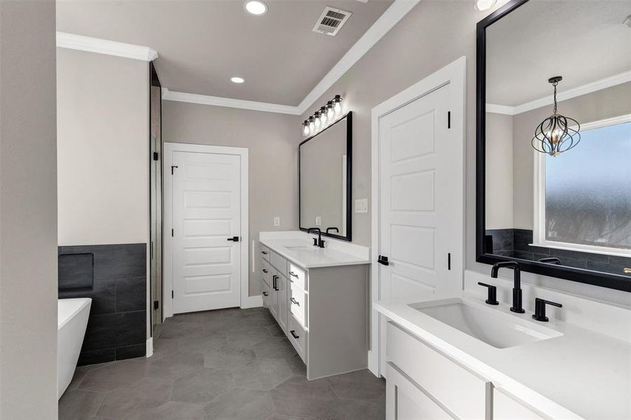 Bathroom with tile walls, tile patterned flooring, vanity, ornamental molding, and a washtub