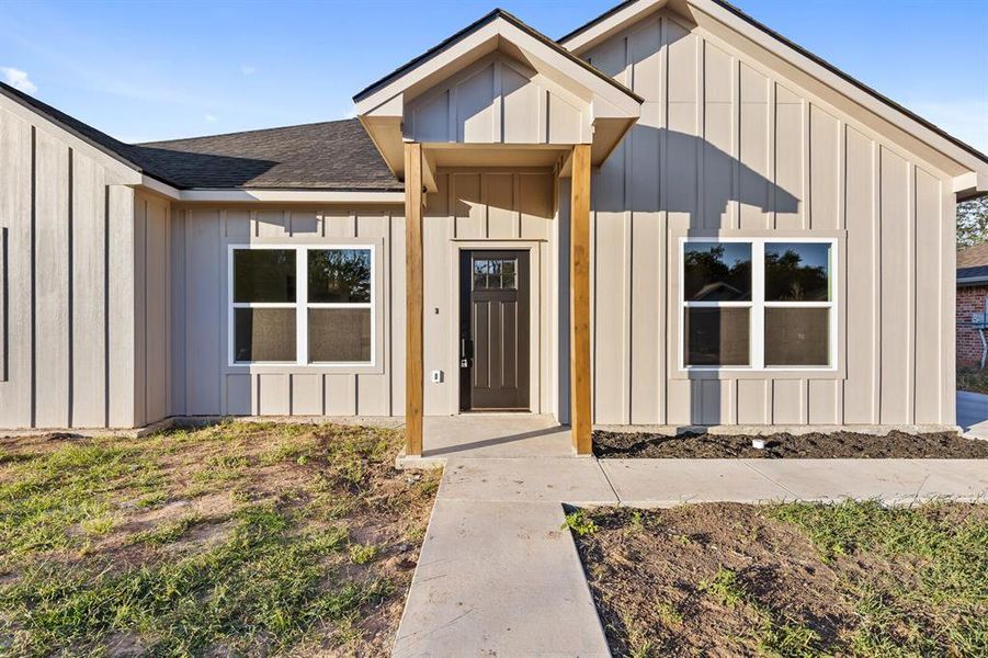 Doorway to property featuring board and batten siding and roof with shingles Doorway to property featuring board and batten siding and roof with shingles