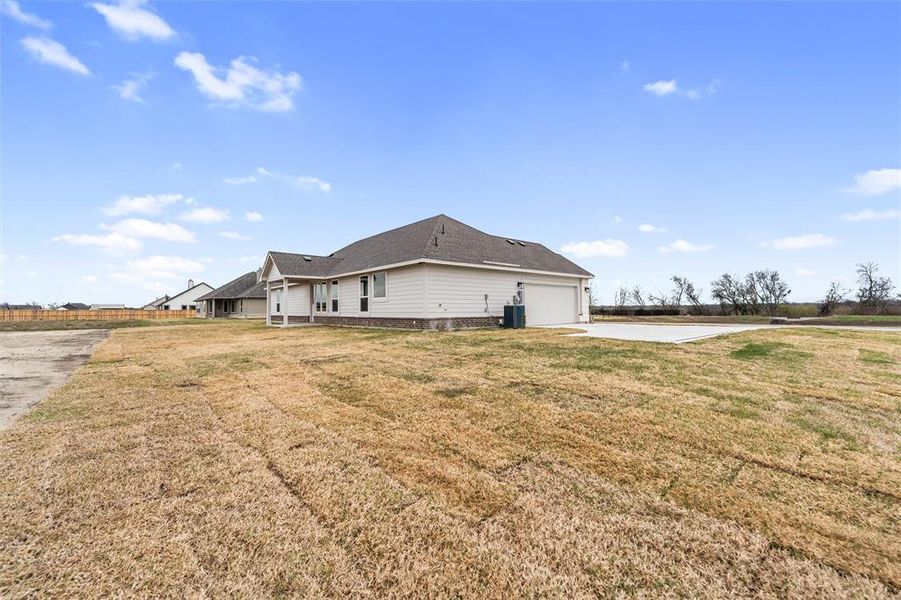 Rear view of house with a yard, concrete driveway, and an attached garage Rear view of house with a yard, concrete driveway, and an attached garage