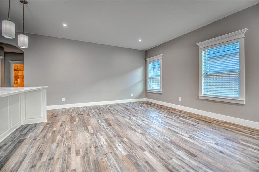 Unfurnished room with light wood finished floors, arched walkways, and recessed lighting