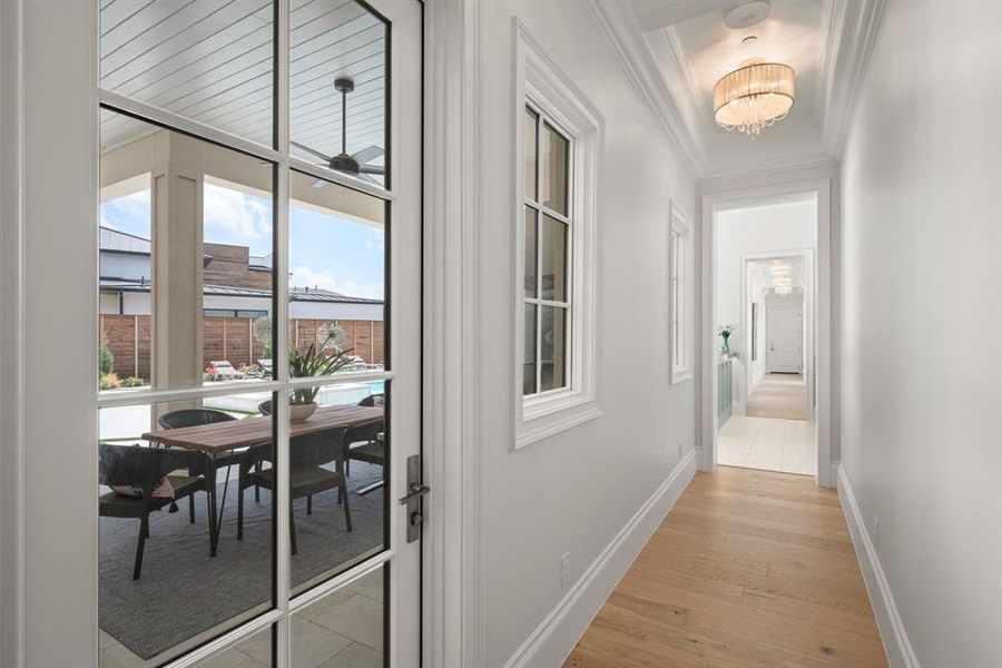 Corridor with ornamental molding, light wood-type flooring, and a chandelier Corridor with ornamental molding, light wood-type flooring, and a chandelier
