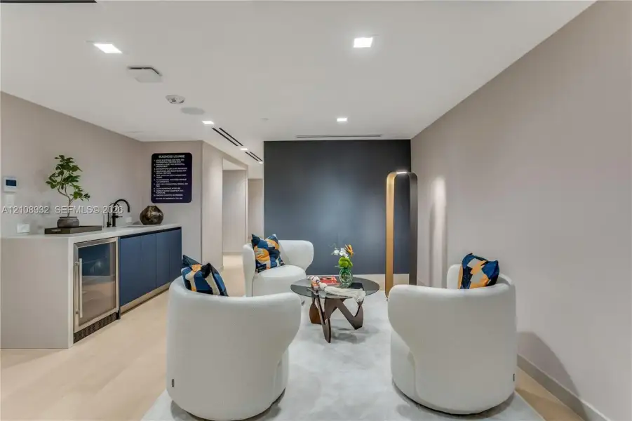 Wet bar featuring navy cabinetry, solid surface countertop, built-in beverage refrigerator, and matte black faucet, accented by recessed lighting and light wood-finish flooring