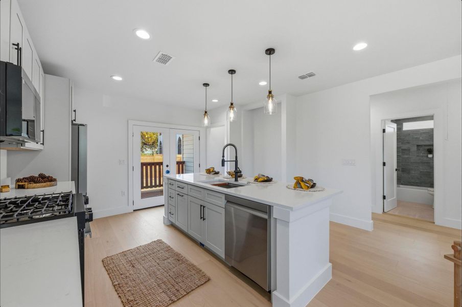 Kitchen with light wood-type flooring, dishwasher, recessed lighting, gas range oven, and decorative light fixtures